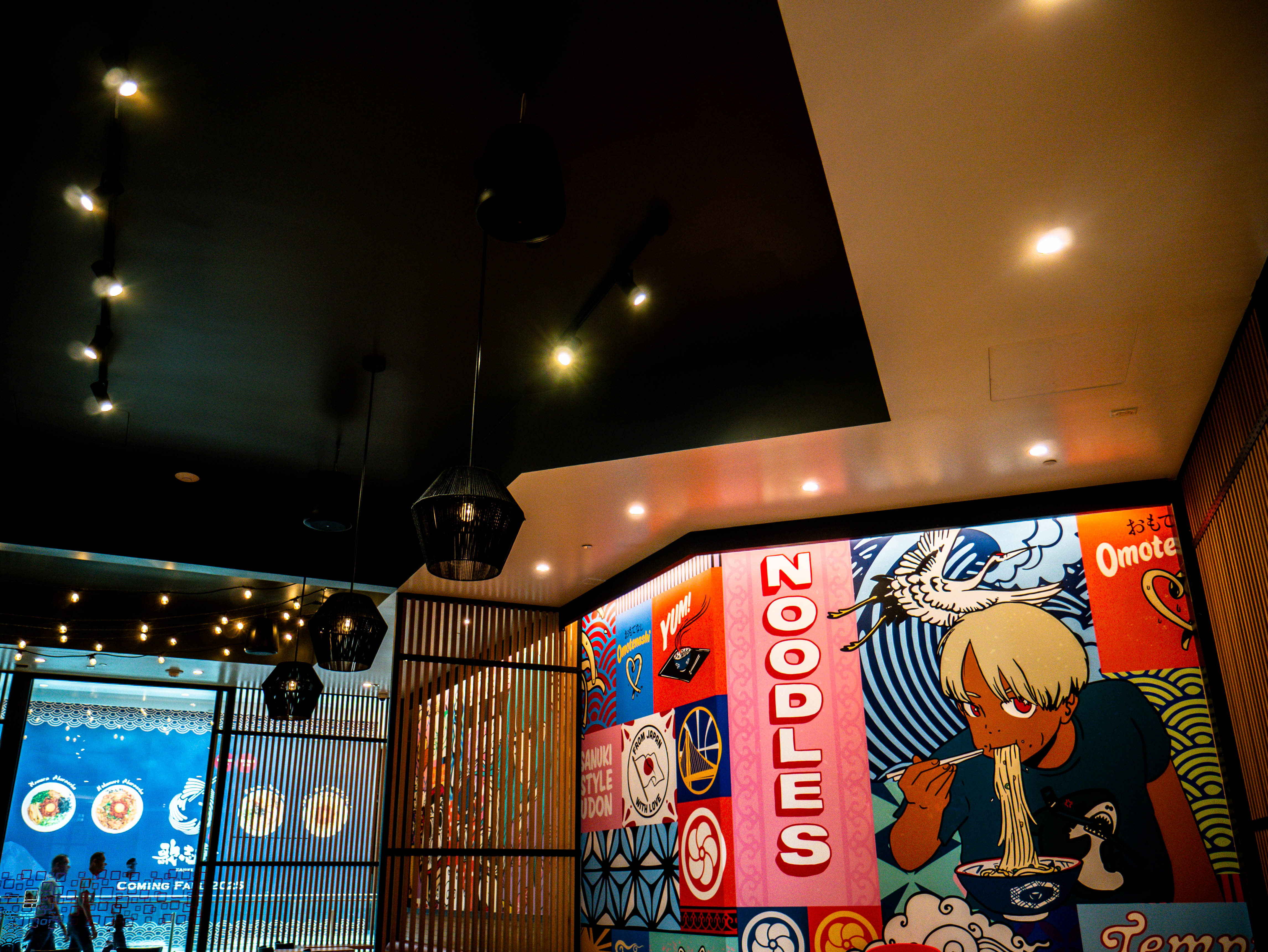 Dining space with extensive colorful murals, wooden slat ceiling design, and modern pendant lighting