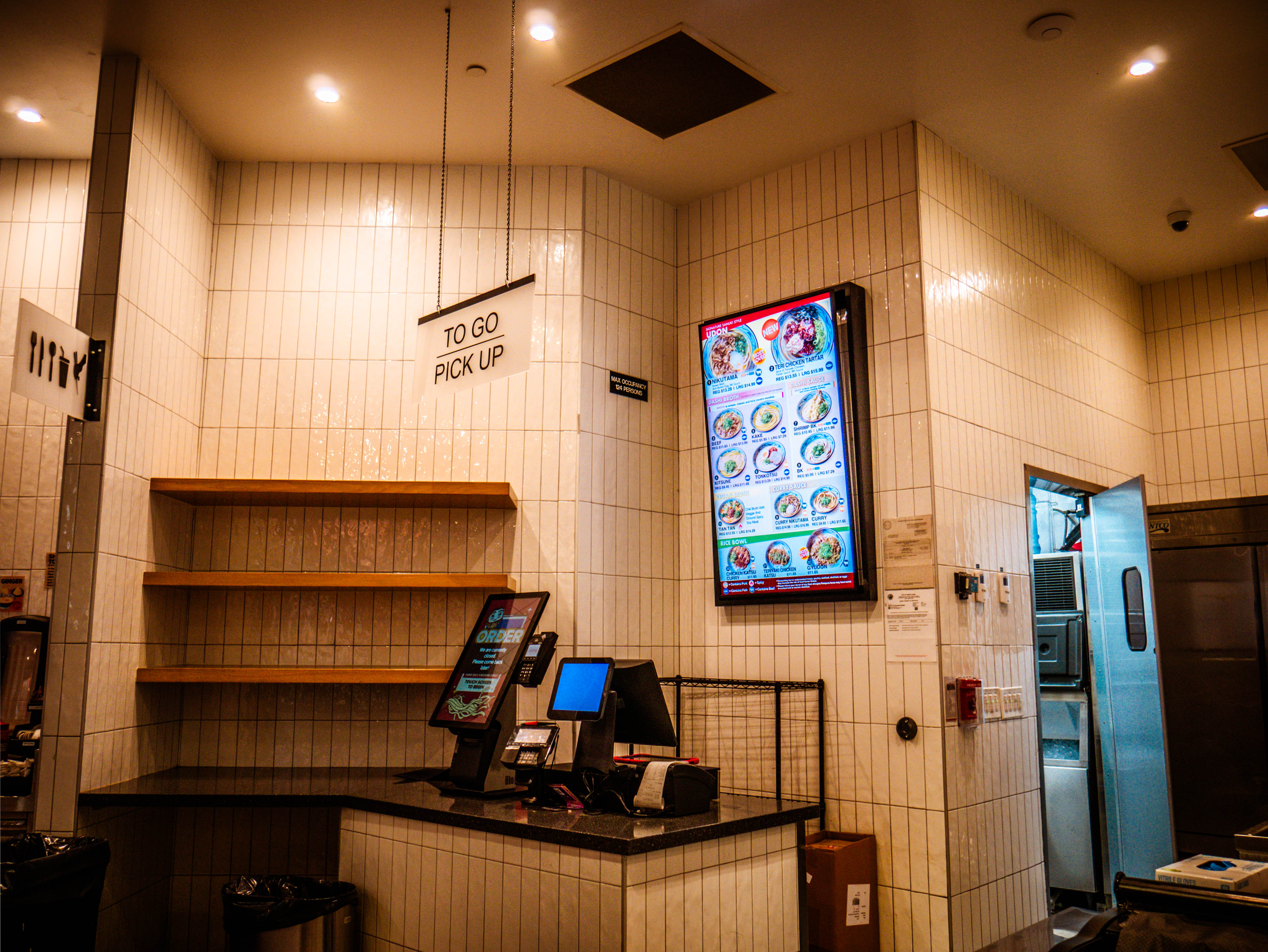 Modern service counter with digital menu displays, POS systems, and efficient to-go pickup area