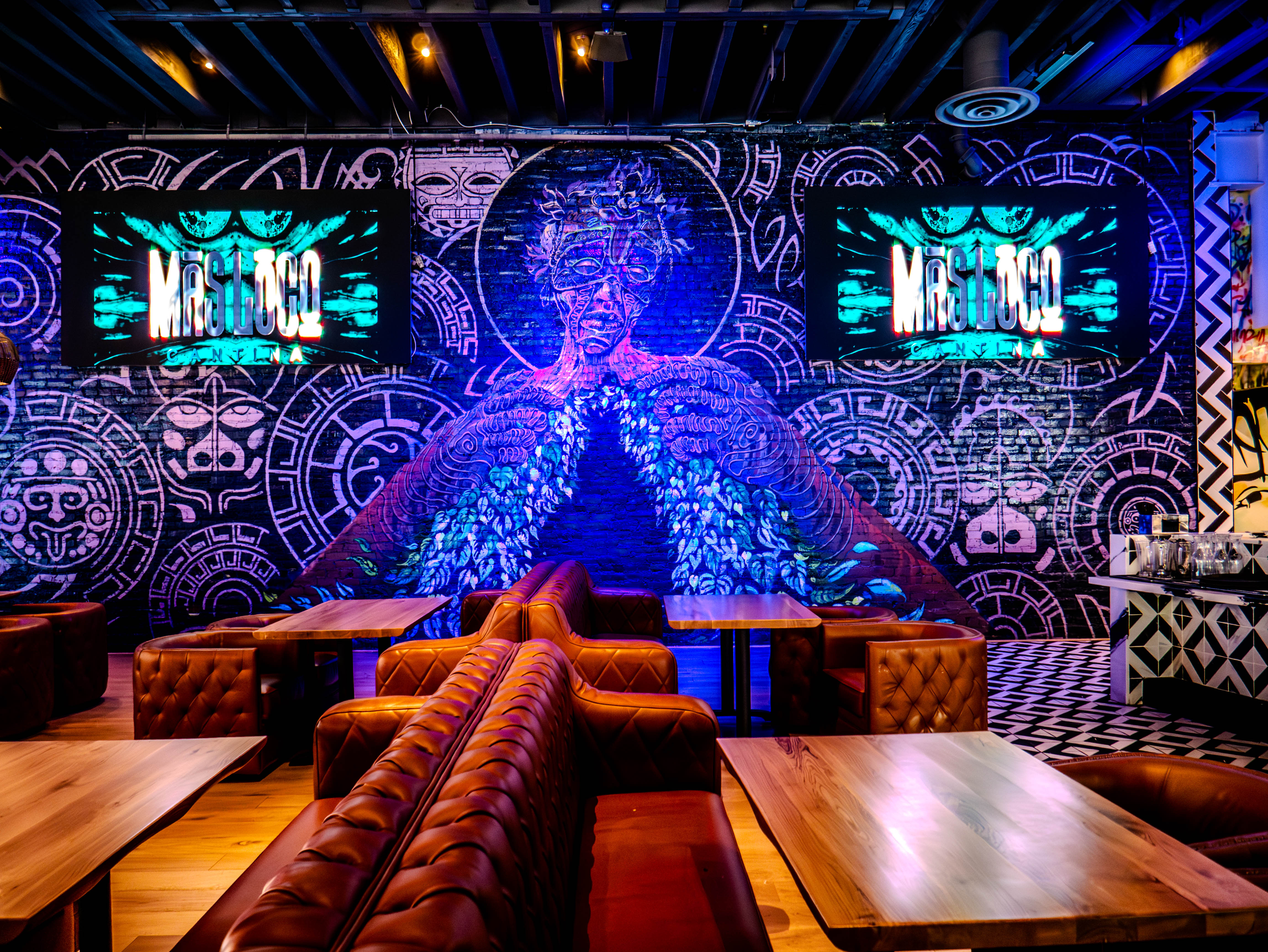 Blue Aztec warrior mural wall with leather seating and multiple TV screens