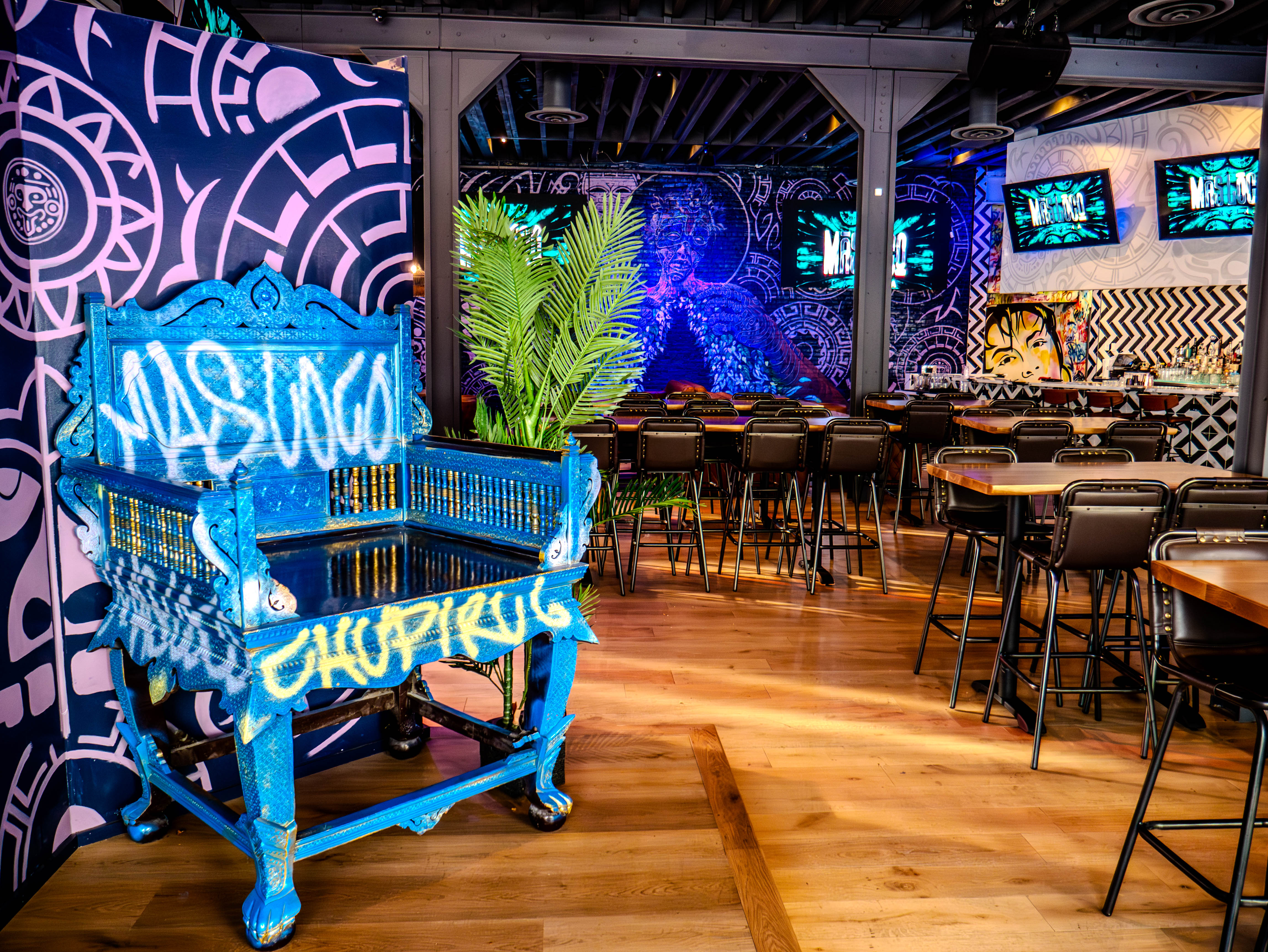 Custom blue painted piano with Mas Loco branding surrounded by high-top seating