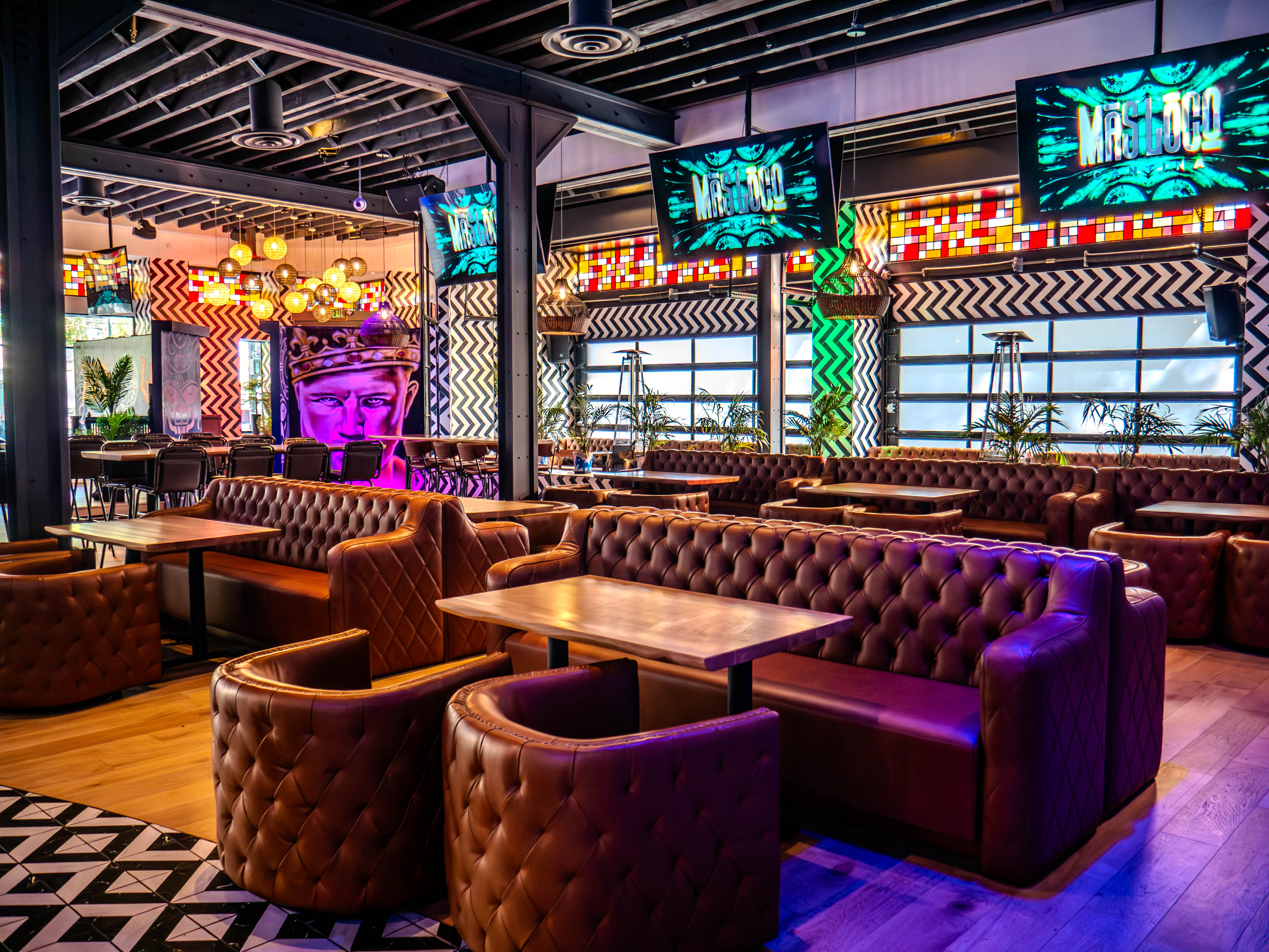 Dining area showcasing luxurious leather seating with colorful stained glass and Aztec murals