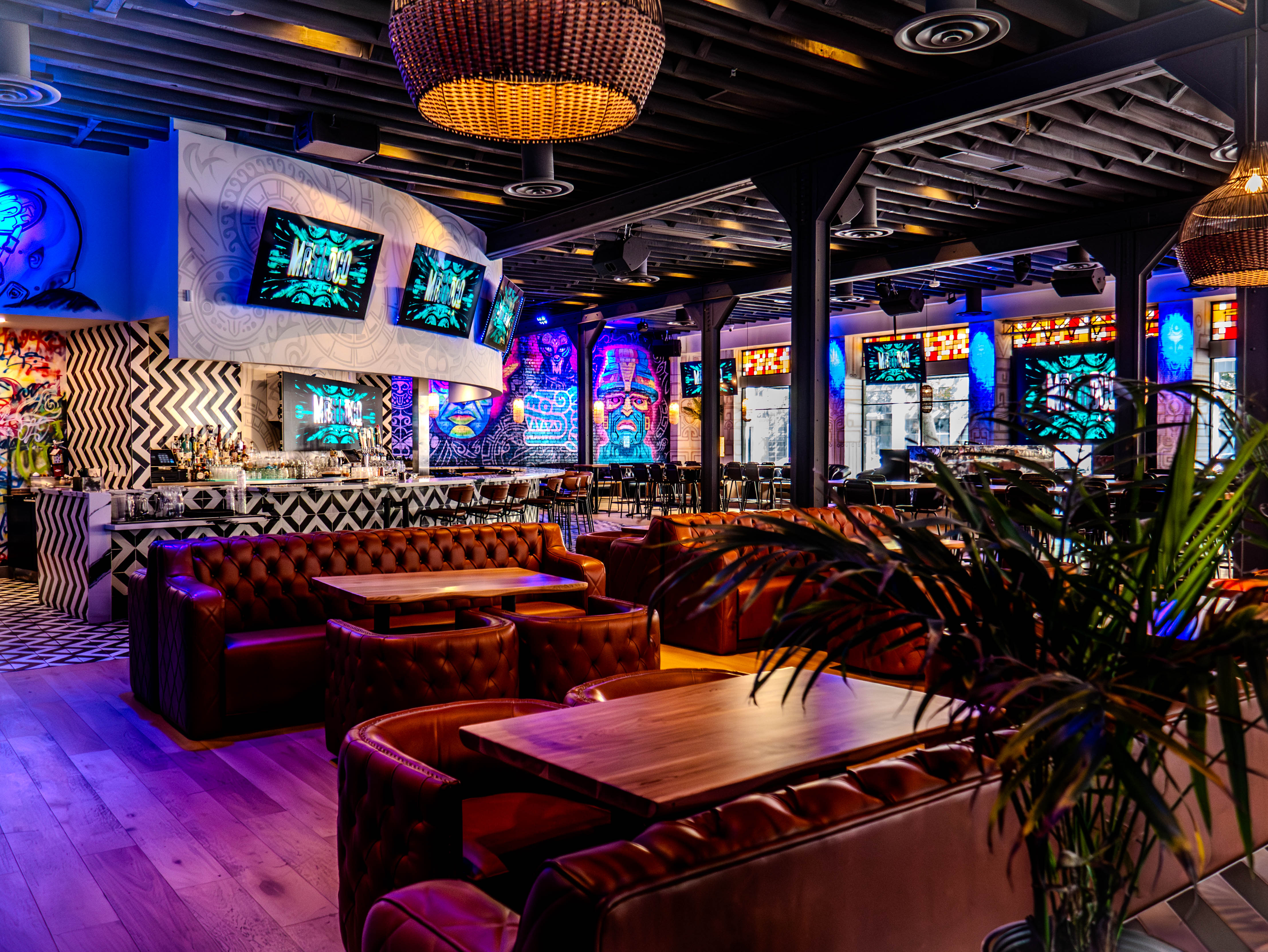 Complete restaurant overview showing extensive leather seating, geometric bar, and Aztec murals