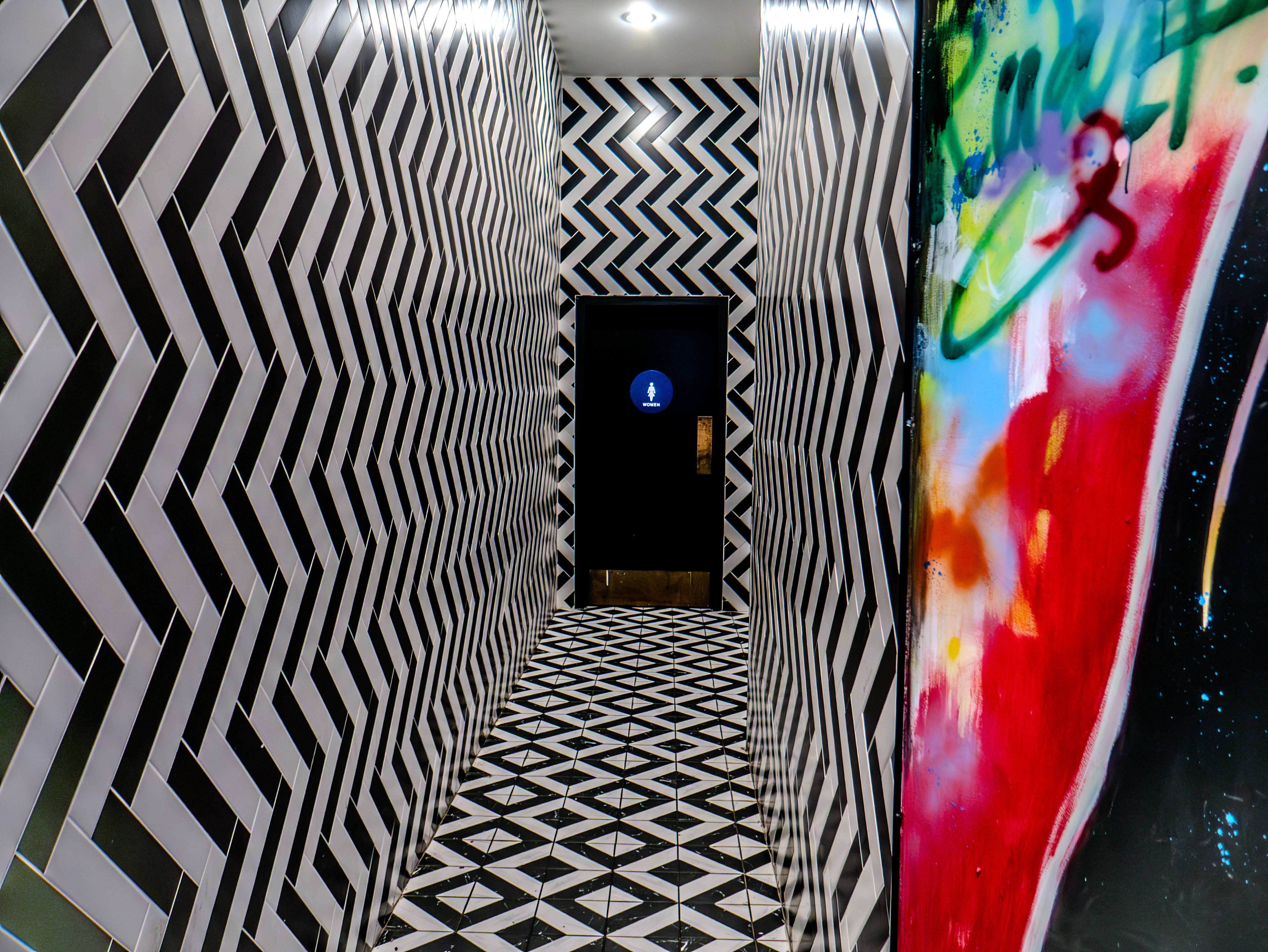 Striking geometric corridor with black and white chevron patterns and diamond flooring