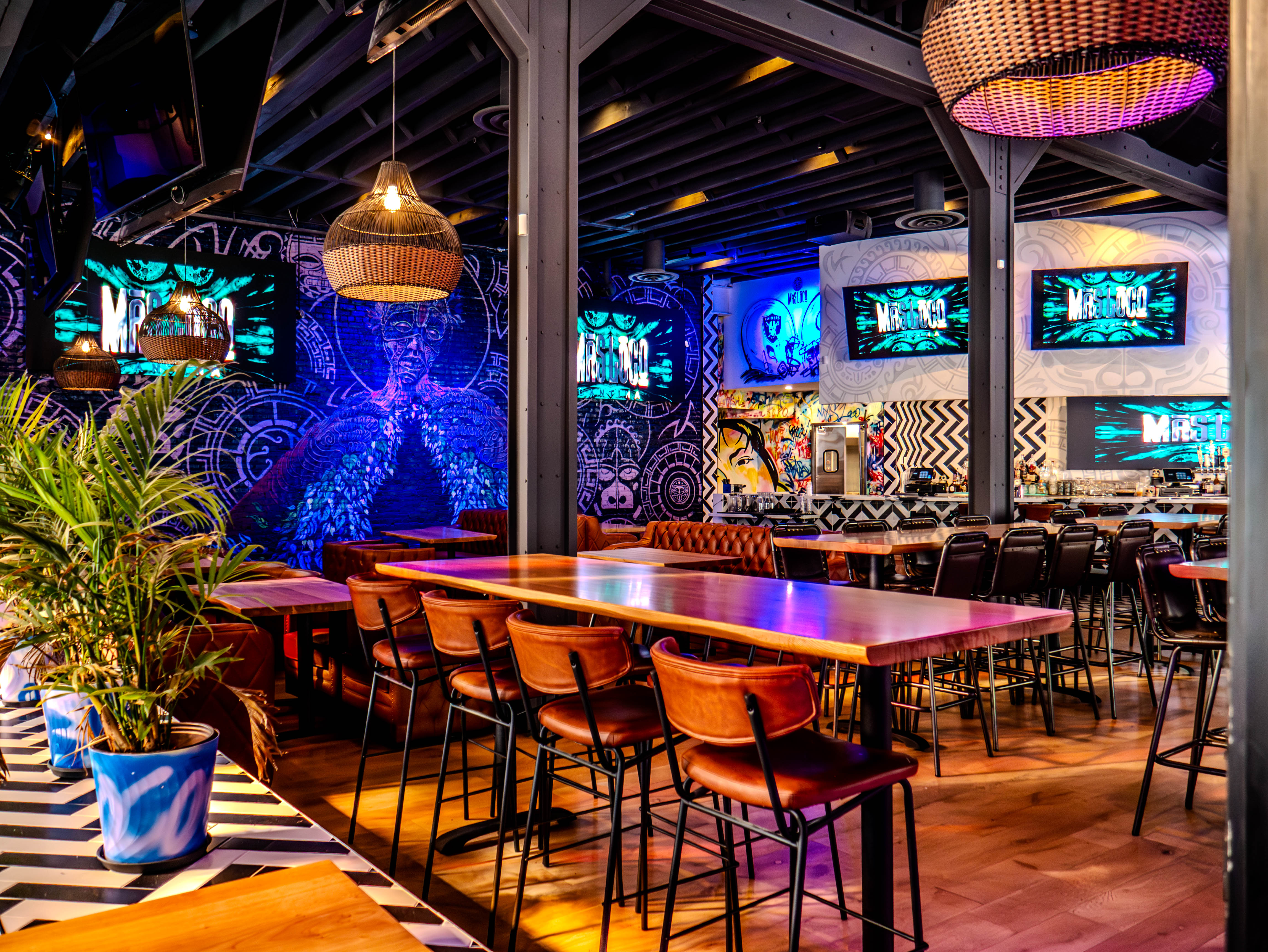 High-top dining area with brown leather chairs and blue Aztec murals