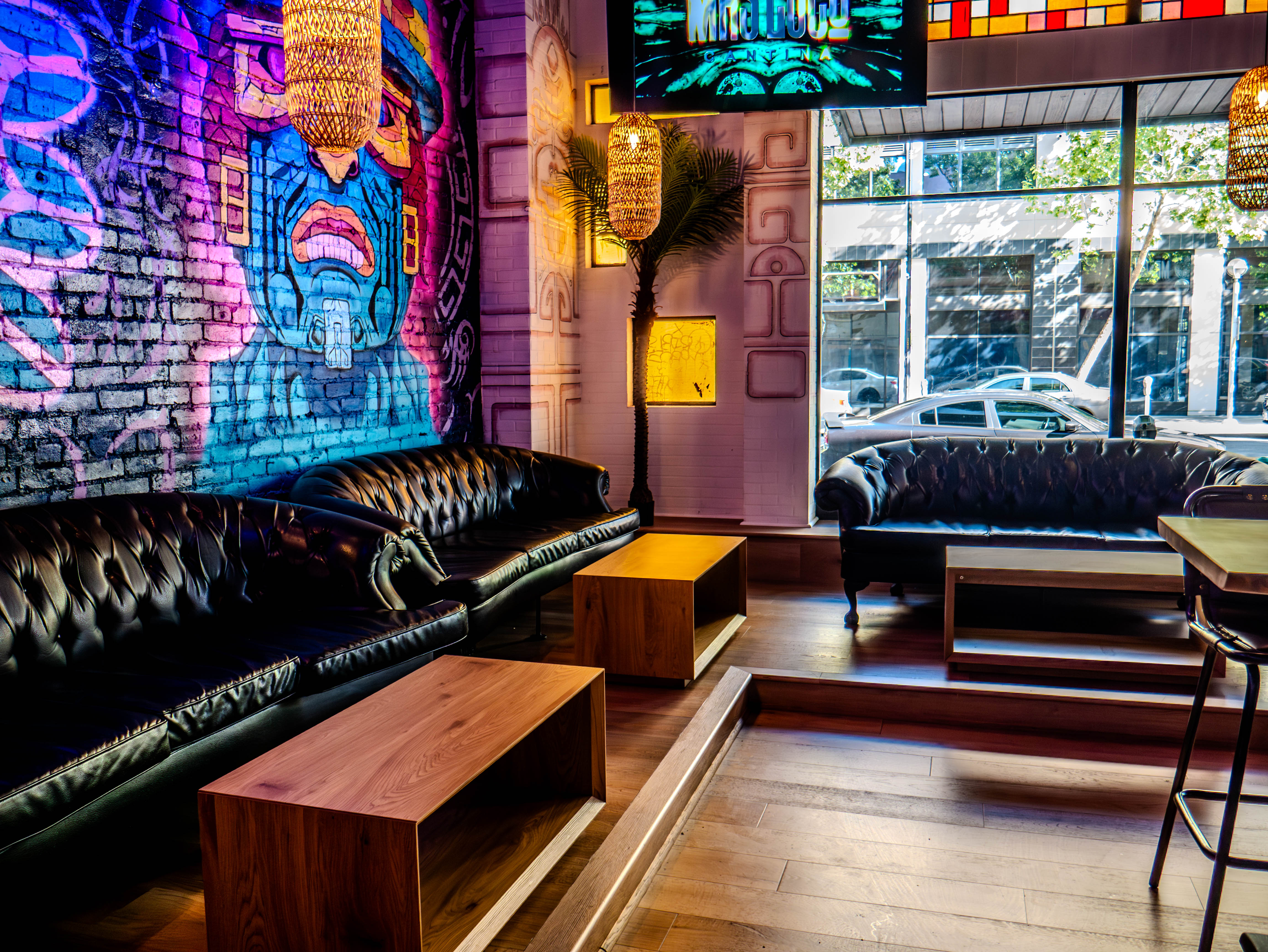 Intimate lounge with black leather seating and colorful murals