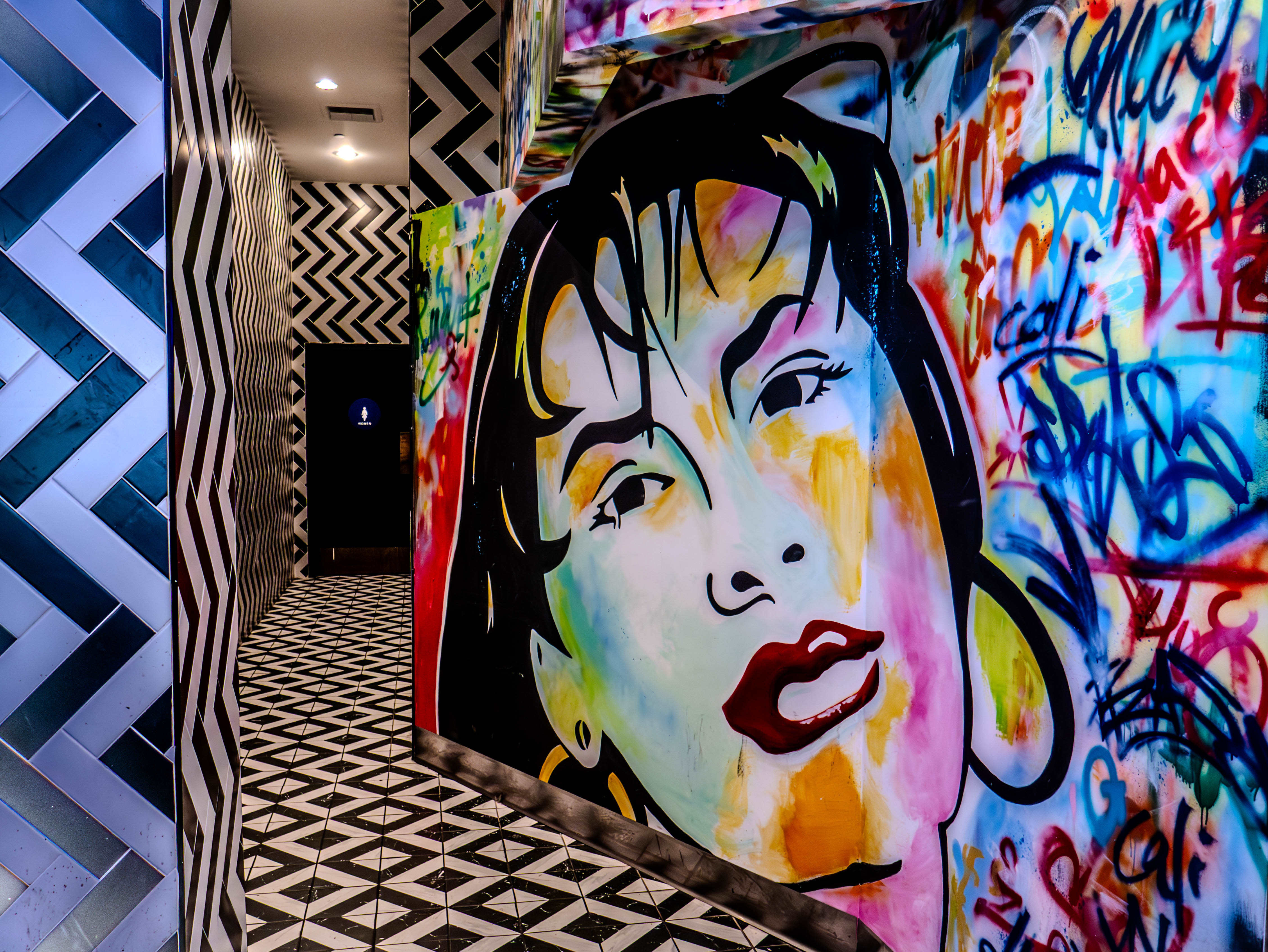 Art corridor featuring vibrant pop art murals and geometric black and white patterns