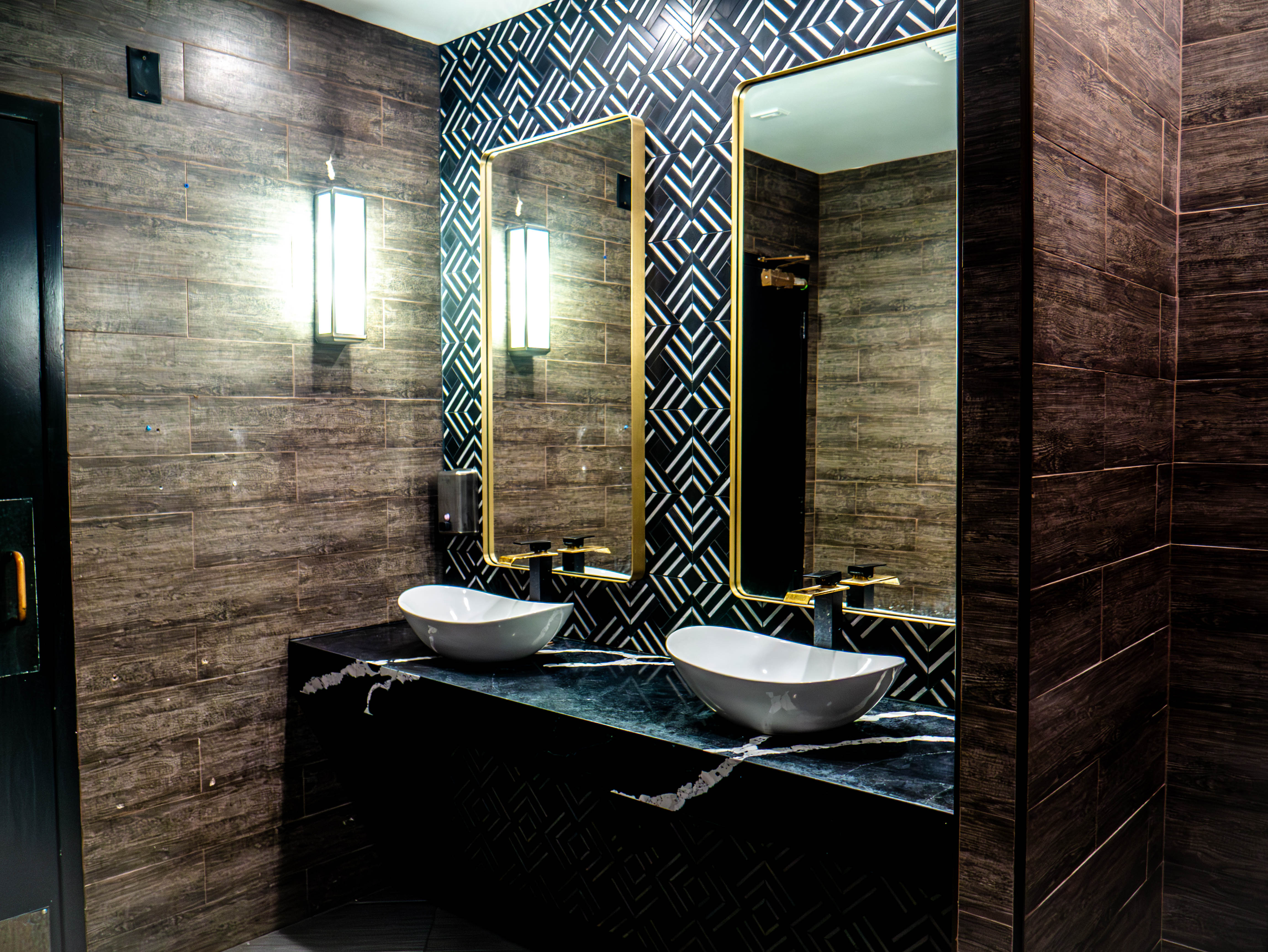 Premium restroom vanity with dual vessel sinks and gold-framed mirrors