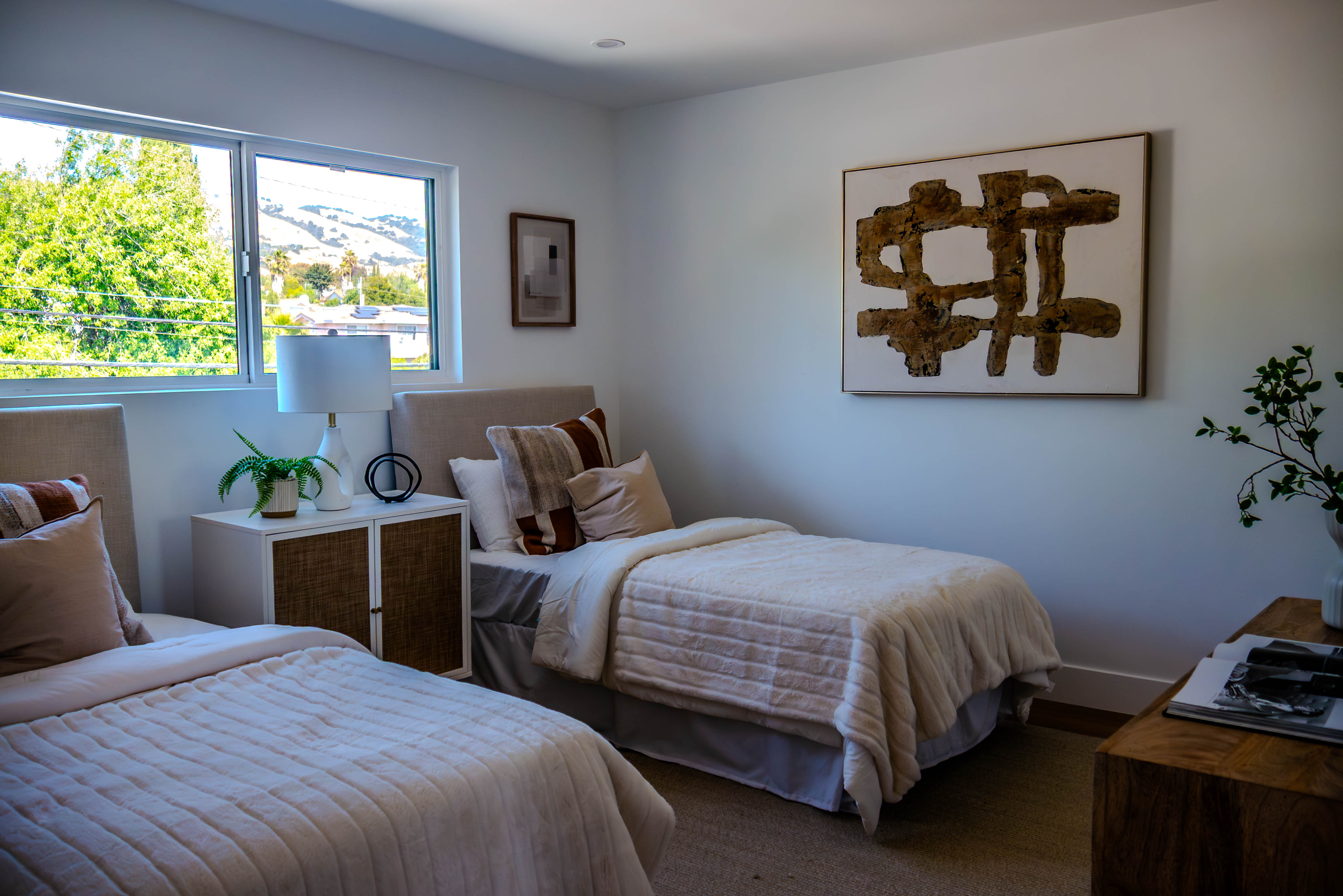 Serene bedroom with twin beds, mountain views, contemporary artwork, and minimalist design