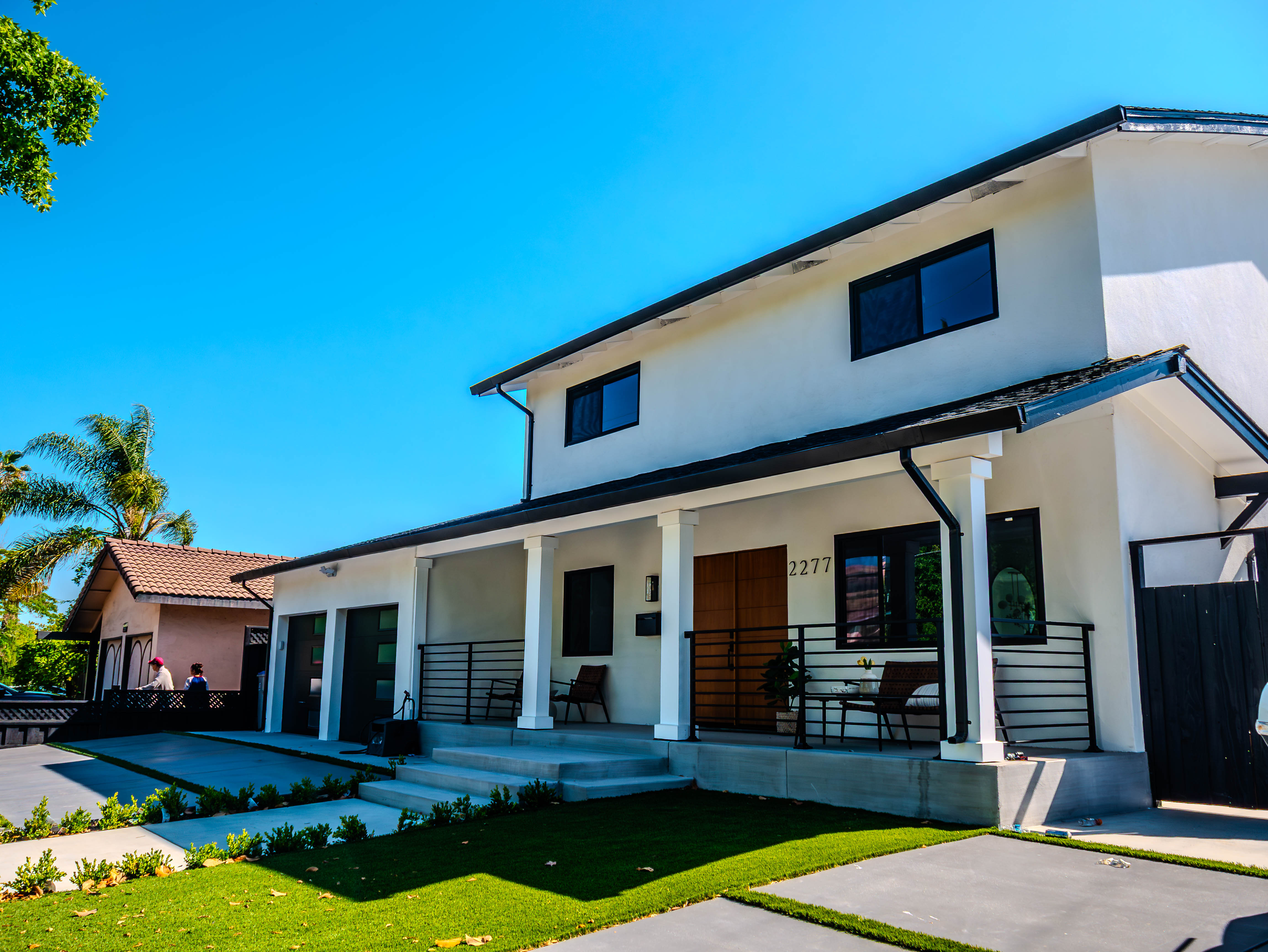 Modern two-story home with white exterior, black trim, and professional landscaping