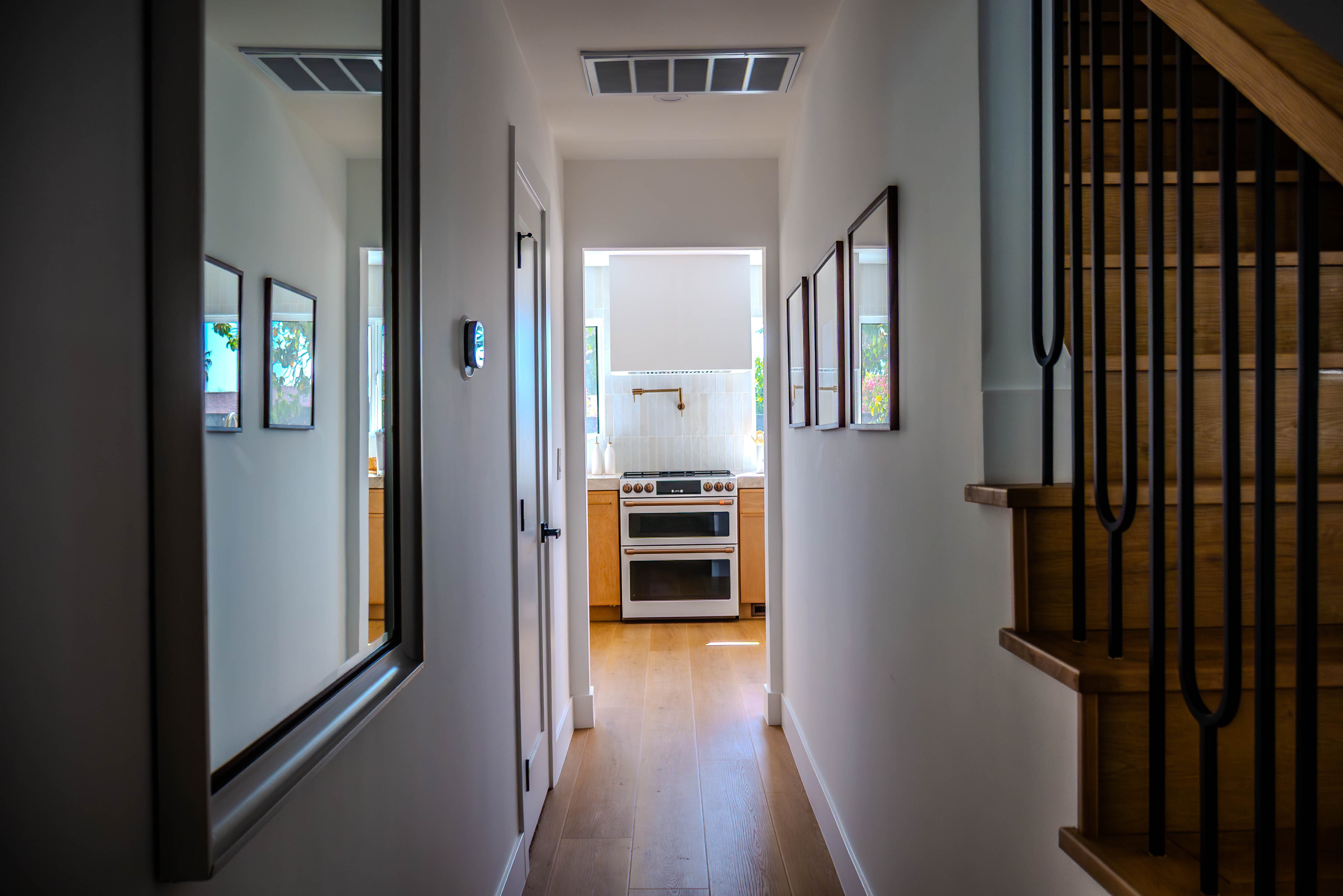 Elegant hallway with hardwood flooring, framed artwork, and view to kitchen, showcasing the home's flow