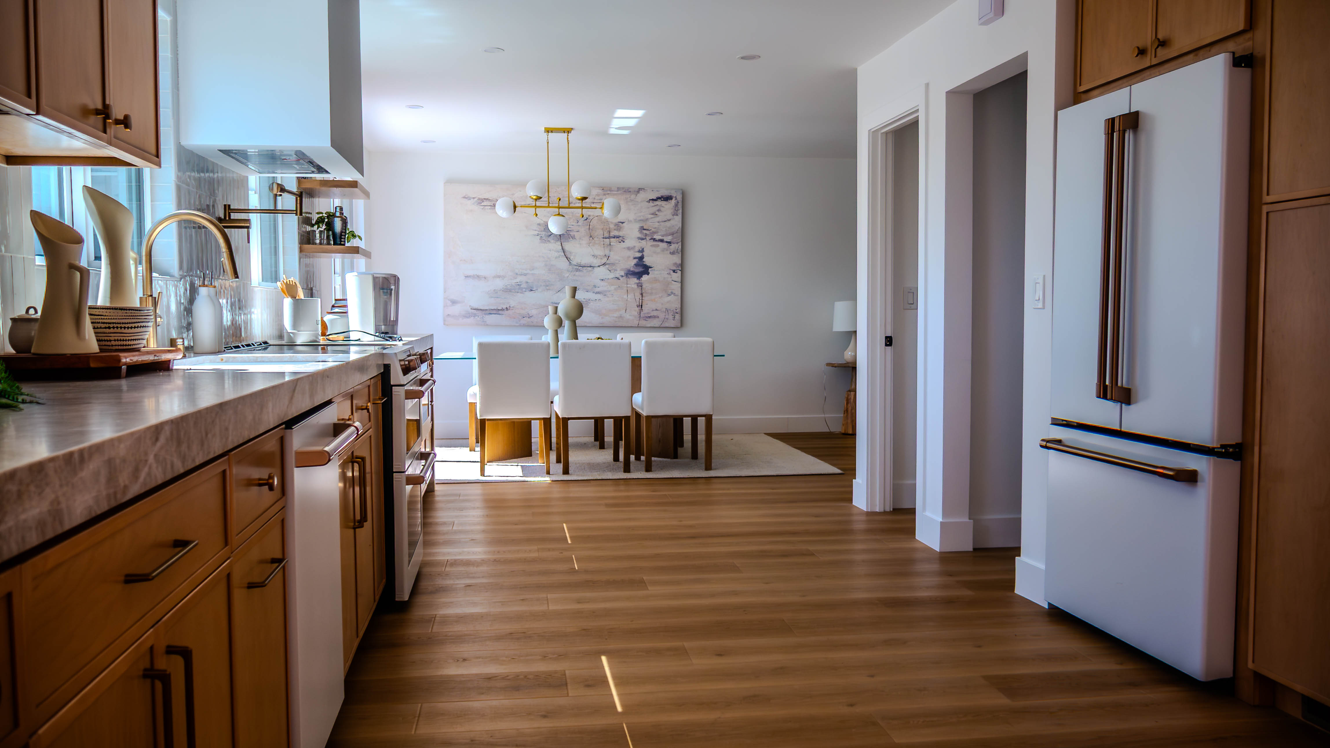 Open concept view showing seamless flow from kitchen to dining area with hardwood flooring and modern lighting