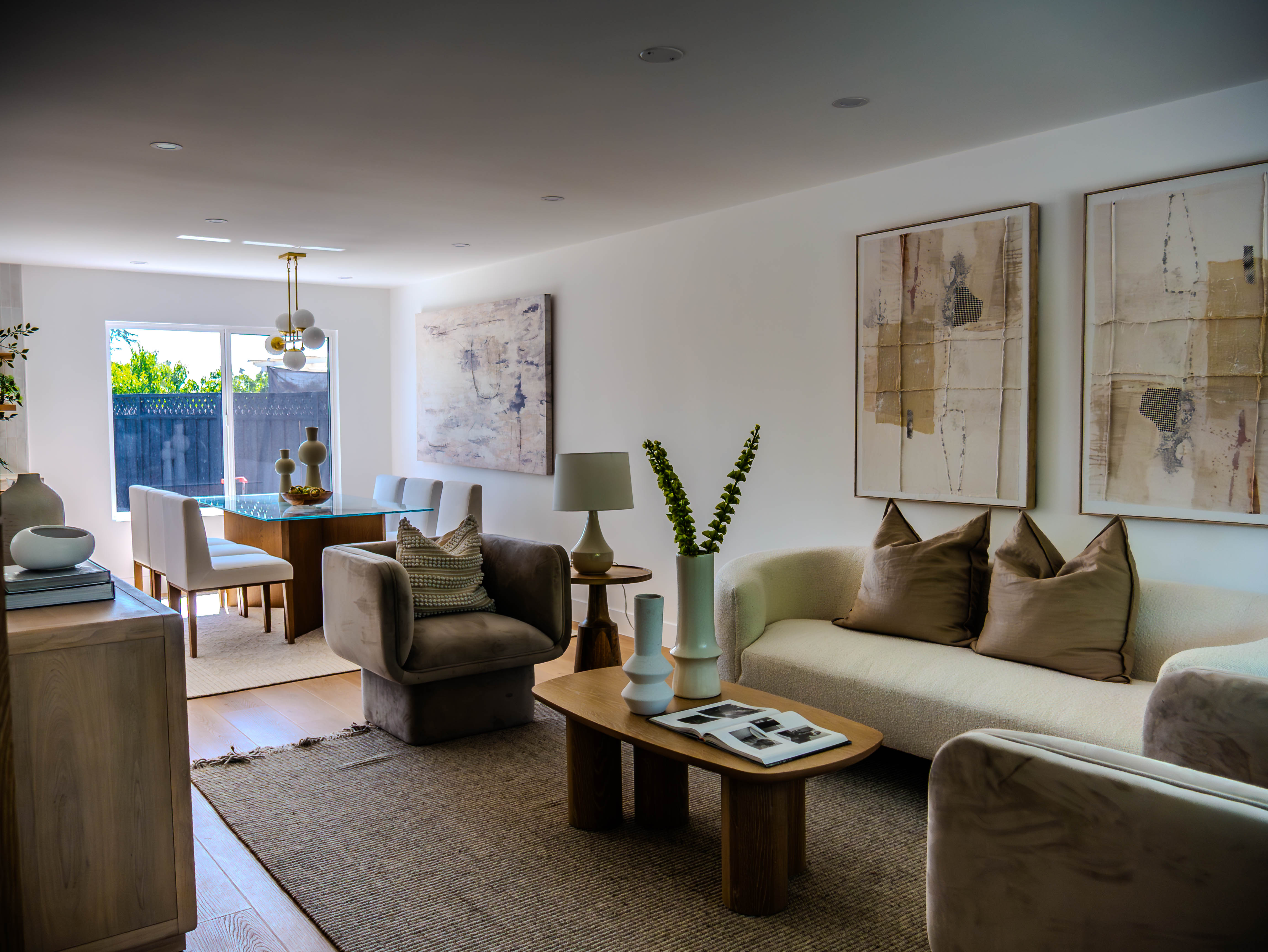 Open concept living and dining area with contemporary artwork, neutral furniture, and sophisticated design