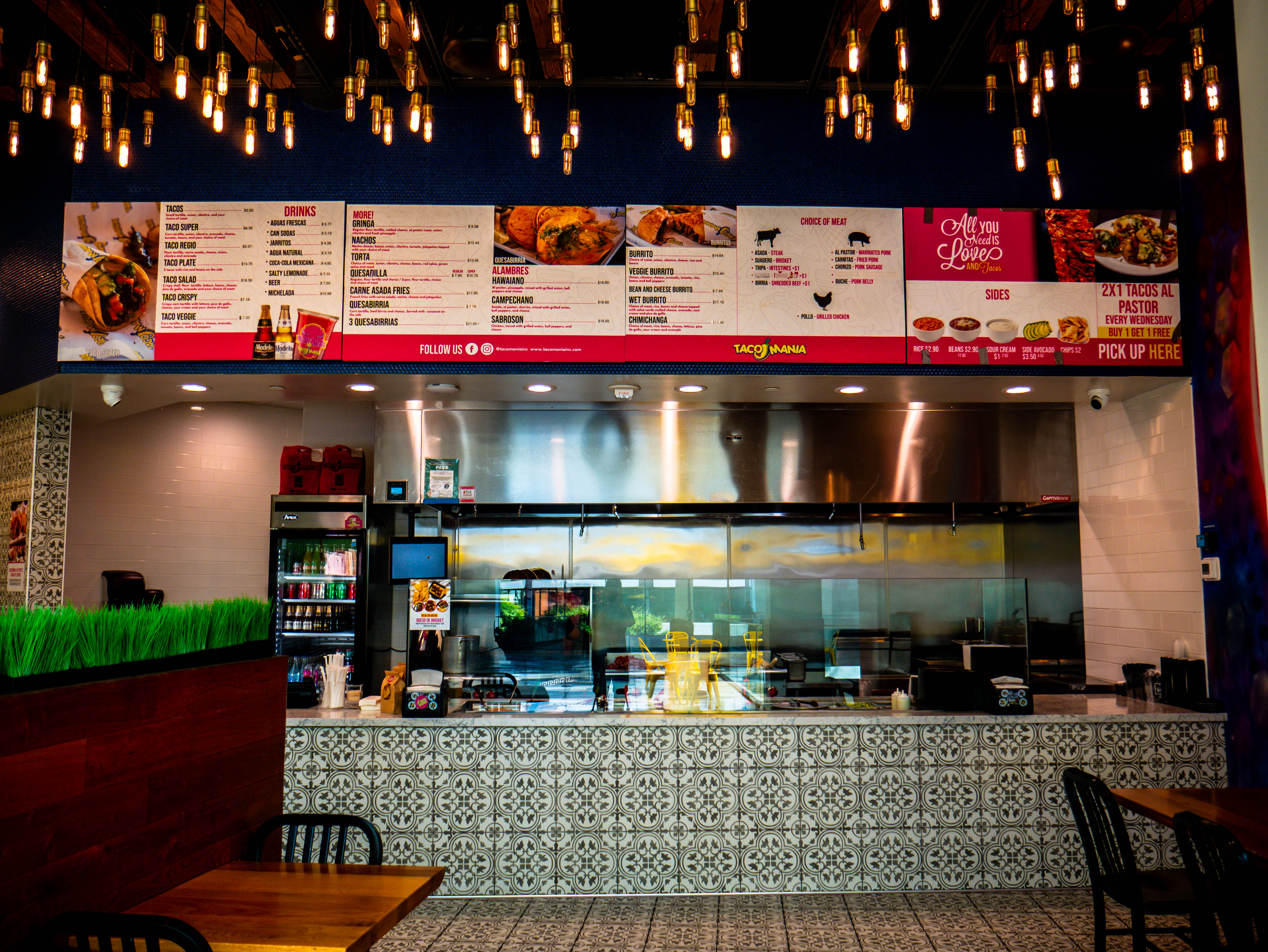 Complete service counter view with full menu board, open kitchen, and extensive Edison bulb ceiling installation