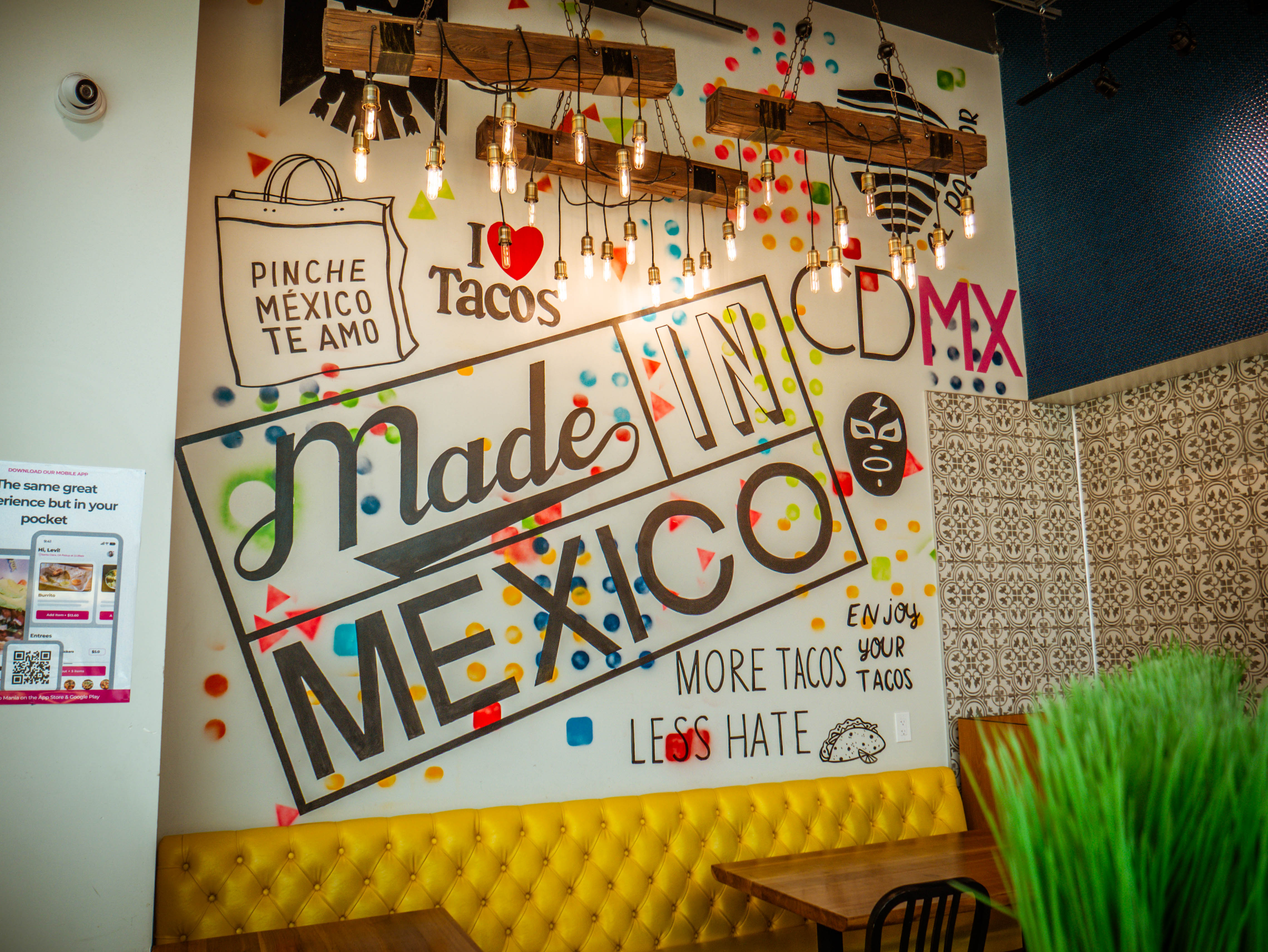 Colorful wall murals featuring 'Made in Mexico' text, 'I Love Tacos', and Mexican cultural graphics with decorative lighting